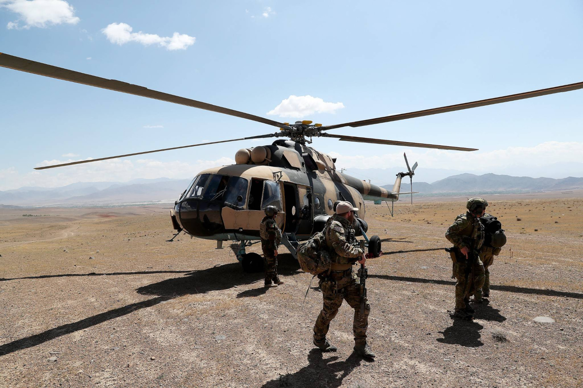 Norwegian Armed Forces personnel beside a transport helicopter on an arid Afghan plain
