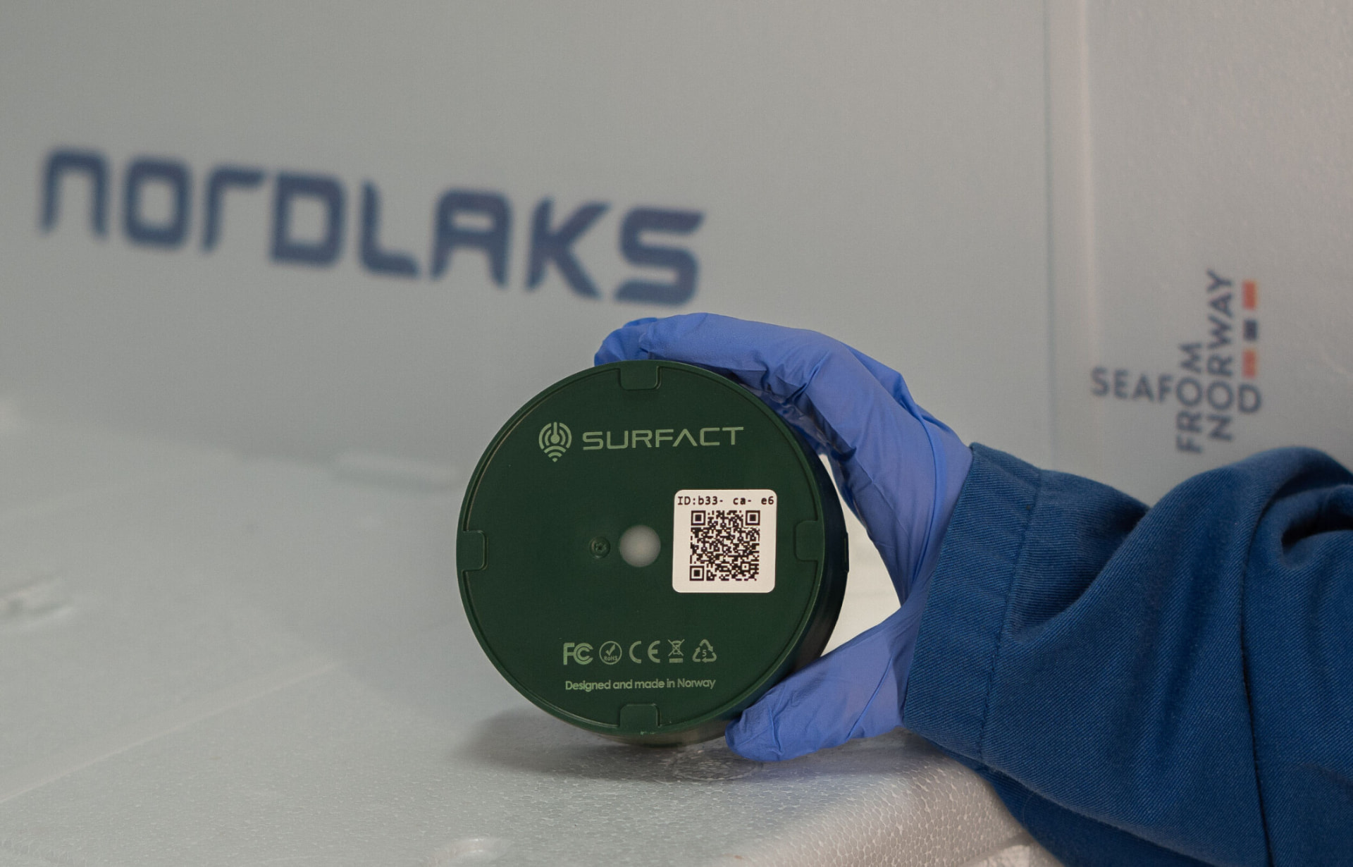 Gloved hand placing the Emma Smart Tracker into a Nordlaks salmon export box