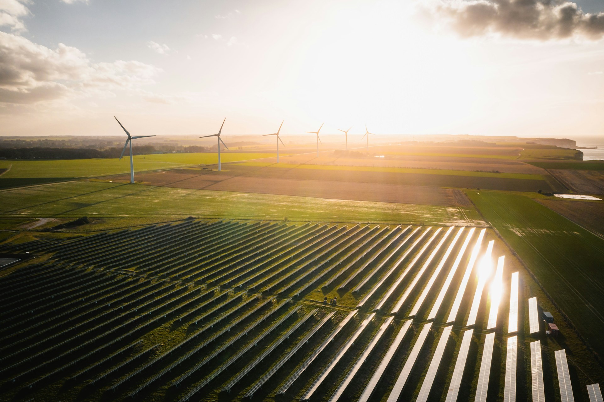 Aerial view of a solar park and wind turbines at sunset